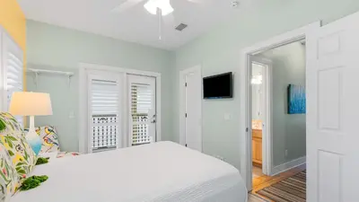 a white bedroom with a bed and a tv at Lemon Drop House in Seacrest