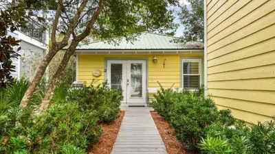 a yellow house with a pathway leading to the door at Lemon Drop House in Seacrest