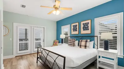 a bedroom with blue walls and a bed with a ceiling fan at Lemon Drop House in Seacrest
