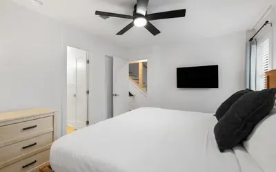 a bedroom with a white bed with a ceiling fan at LakeTide Retreat in Santa Rosa Beach