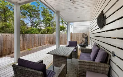 a porch with chairs and a table and a fence at Occasionally Luxe in Seacrest