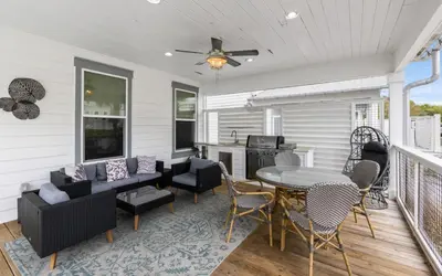 a screened in porch with a table and chairs at Occasionally Luxe in Seacrest