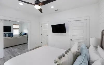 a white bedroom with a couch and a flat screen tv at Occasionally Luxe in Seacrest