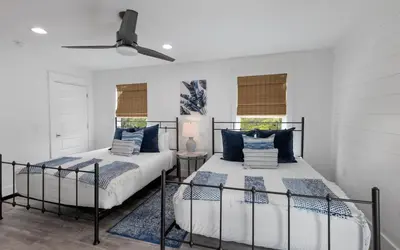 two beds in a room with two windows at Occasionally Luxe in Seacrest
