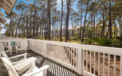 a porch with two white chairs and trees at Once Upon A Tide in Inlet Beach