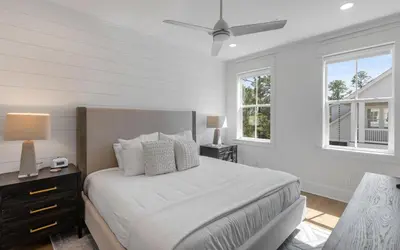 a white bedroom with a bed and two windows at Out of Office in Santa Rosa Beach