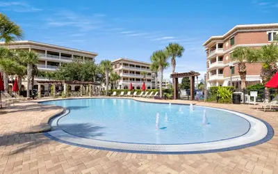 a swimming pool in a resort with palm trees and buildings at Peanuts Place in Seacrest