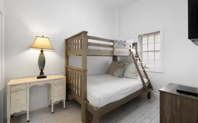 a bedroom with a bunk bed and a desk with a lamp at Peanuts Place in Seacrest