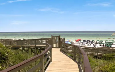 a wooden boardwalk leading to a beach with people on it at Peanuts Place in Seacrest