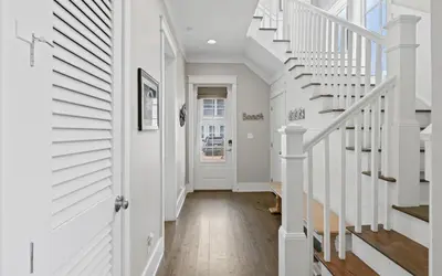 a hallway with white walls and white staircases at Pirates Smile in Rosemary Beach