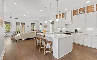 a kitchen with white cabinets and a kitchen island with bar stools at Pirates Smile in Rosemary Beach