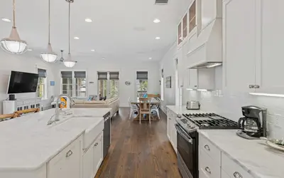 a large kitchen with white counter tops and a table at Pirates Smile in Rosemary Beach