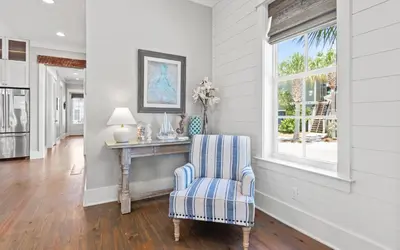 a living room with a table and a chair at Pirates Smile in Rosemary Beach