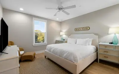 a white bedroom with a bed and a television at Saltwater Song in Santa Rosa Beach