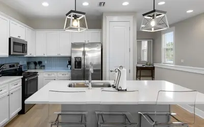 a kitchen with white cabinets and a stainless steel refrigerator at Saltwater Song in Santa Rosa Beach