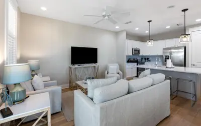 a living room with a couch and a kitchen at Saltwater Song in Santa Rosa Beach