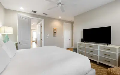 a bedroom with a white bed and a flat screen tv at Saltwater Song in Santa Rosa Beach
