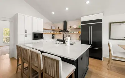 a kitchen with a large island with chairs and a black refrigerator at Sea n Stars in Seacrest