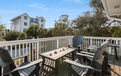 a table and chairs on a deck with a white fence at Sea n Stars in Seacrest