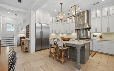 a kitchen with white cabinets and a kitchen island with chairs at Sundance in Inlet Beach