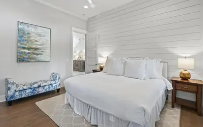 a white bedroom with a bed and a chair at Sundance in Inlet Beach