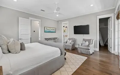 a white bedroom with a bed and two chairs at Sundance in Inlet Beach