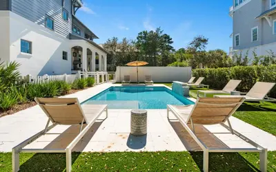 a backyard with a swimming pool and two chairs at Sundance in Inlet Beach