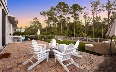 a patio with four white chairs and a table at Surf Sanctuary in Santa Rosa Beach