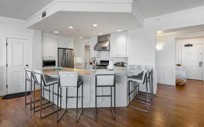 a kitchen with white cabinets and a island with bar stools at The Crossings at Watersound Beach C214 in Inlet Beach