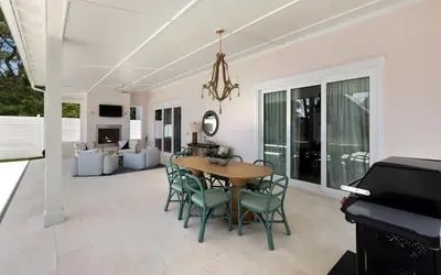 a dining room with a table and chairs and a piano at Tickled Pink in Santa Rosa Beach