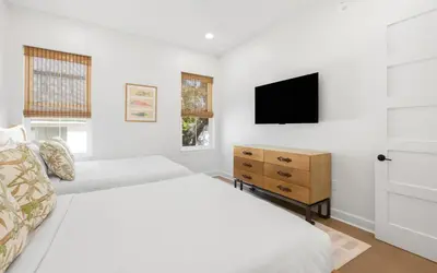 a white bedroom with two beds and a tv at Tickled Pink in Santa Rosa Beach