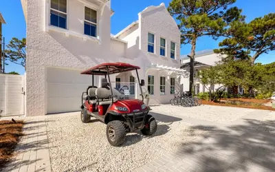 a red golf cart parked in front of a house at Tickled Pink in Santa Rosa Beach
