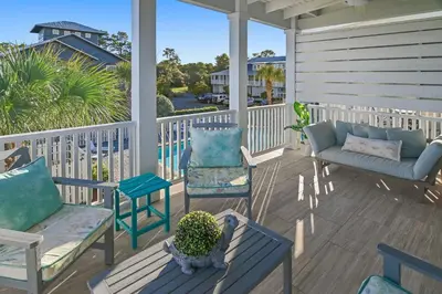 a porch with chairs and a couch and a table at Sea Turtle House- Lux Townhome- Pool - Golf Cart in Santa Rosa Beach