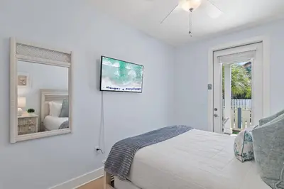 a white bedroom with a bed and a mirror at Sea Turtle House- Lux Townhome- Pool - Golf Cart in Santa Rosa Beach