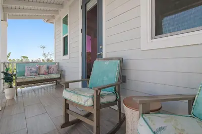two chairs sitting on the porch of a house at Sea Turtle House- Lux Townhome- Pool - Golf Cart in Santa Rosa Beach