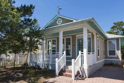 a small green and white house with a porch at Rise and Shine in Santa Rosa Beach