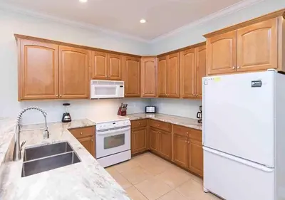 a kitchen with wooden cabinets and a white refrigerator at Rise and Shine in Santa Rosa Beach