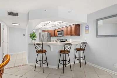 a kitchen with two bar stools and a counter at Breathtaking Sunset View Beachfront Condo Resort in Panama City Beach
