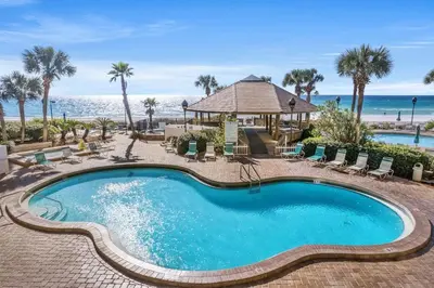 a swimming pool with chairs and the beach at Breathtaking Sunset View Beachfront Condo Resort in Panama City Beach