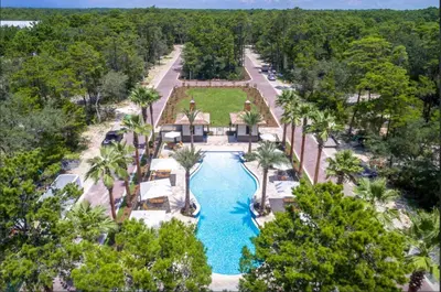 an aerial view of a resort pool with palm trees at Sleeps 18 | Bikes | Sunshine State of Mind | 30A | Pool | Beach Access in Inlet Beach