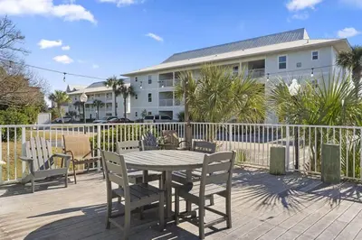 a table and chairs on a deck in front of a house at You are my Sunshine- Heated Pool- Steps to sand in Santa Rosa Beach