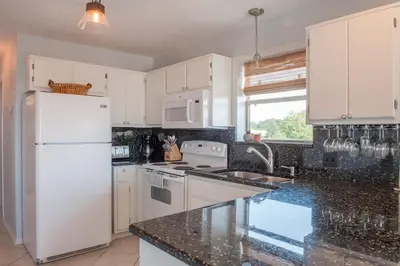a kitchen with white appliances and a black counter top at You are my Sunshine- Heated Pool- Steps to sand in Santa Rosa Beach