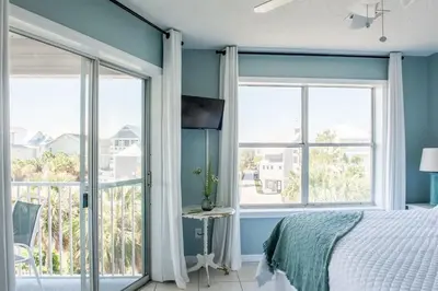 a bedroom with blue walls and large windows and a bed at You are my Sunshine- Heated Pool- Steps to sand in Santa Rosa Beach