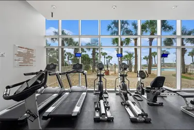 a gym with several treadmills and a large window at Gulf-Front Paradise, Steps to Beach & Pool Access in Panama City Beach