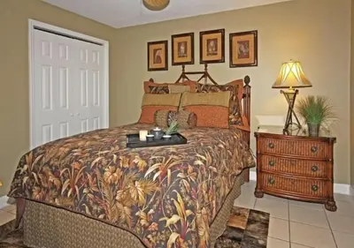 a bedroom with a bed and a dresser with a lamp at Gulf-Front Paradise, Steps to Beach & Pool Access in Panama City Beach