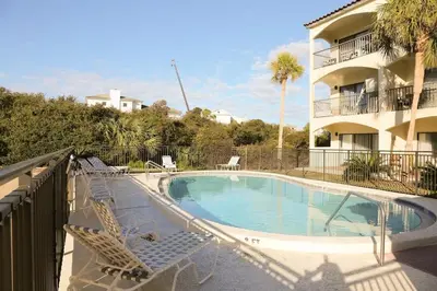 a swimming pool with two lounge chairs and a building at 2 The Sea- Private Beach- Pool in Santa Rosa Beach