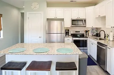 a kitchen with white cabinets and a counter with blue plates on it at 2 The Sea- Private Beach- Pool in Santa Rosa Beach