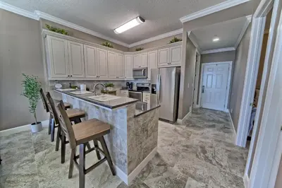 a kitchen with white cabinets and a counter with chairs at Ocean Reef in Panama City Beach
