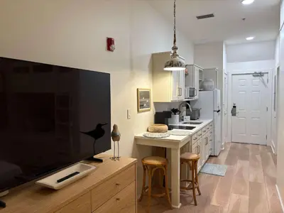 a kitchen with a large tv and a counter with stools at The Inn at Seacrest Beach Unit 207 in Rosemary Beach