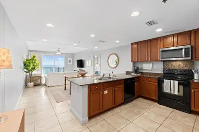 an open kitchen and living room with a couch at Sterling Breeze 607 | Gulf-Front 3BR Condo | 6th Floor Balcony, Infinity Pool, Direct Beach Access in Panama City Beach